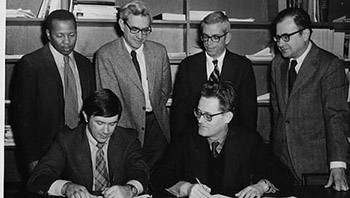 black and white photo of people signing agreement