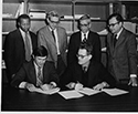 black and white photo of people signing agreement