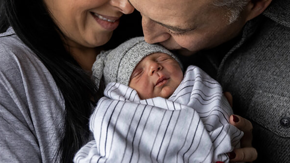 two people holding a newborn baby