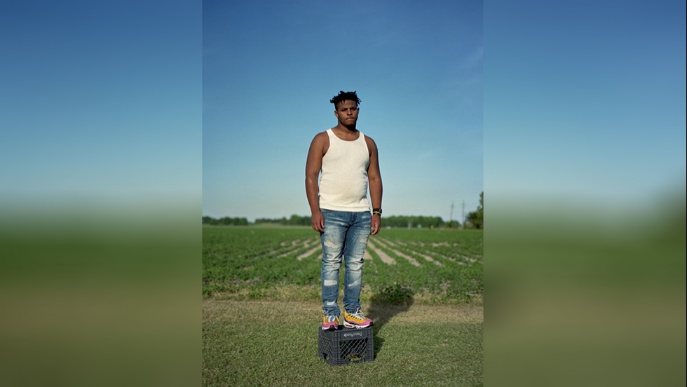 man standing on a milk crate in a field